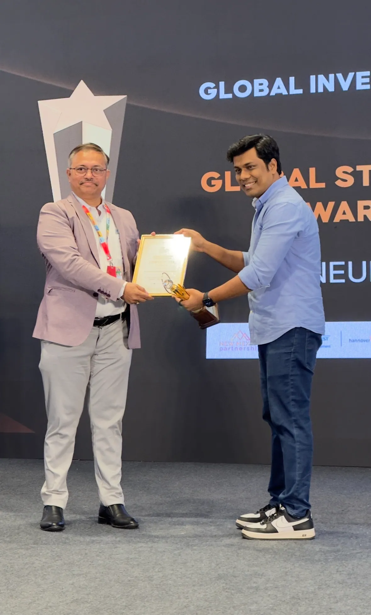 Bibek Nayak, CEO of NeuronX Research, receives the award on stage.